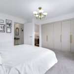 Elegant bedroom with modern decor and chandelier.