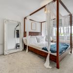 Elegant bedroom with four-poster bed and mirror.