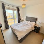 Bright bedroom with double bed and large window.