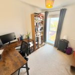 Home office with desk, bookshelf, and window view.