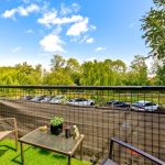 Garden balcony overlooking trees and parked cars.
