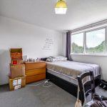Cosy bedroom with bed, window, and storage boxes.