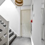 Carpeted stairs in bright hallway with door.