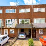 Brick terrace houses with parked cars in driveway.