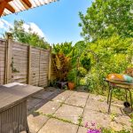 Sunny garden patio with barbecue and table.