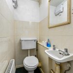 Compact bathroom with toilet, sink, and mirror