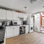 Modern kitchen with appliances and garden access.