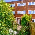 Back garden of red brick house with greenery.