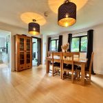 Spacious dining room with wooden table and pendant lights.