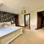 Cosy bedroom with floral wallpaper and en-suite bathroom.