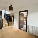 Modern home hallway with staircase and open door.