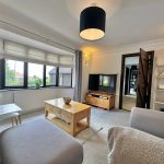 Bright living room with TV, bay window, modern decor.