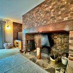 Cosy living room with brick fireplace and TV.
