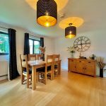 Dining room with wooden furniture and wall clock.