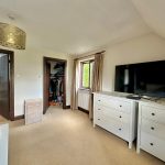Bedroom with ensuite and large TV on dresser.