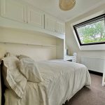 Bright bedroom with sloped window and double bed.