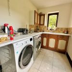 Utility room with appliances and cleaning supplies.