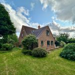 Brick house with gardens and cloudy sky