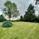 Lush green garden with trees and cloudy sky.