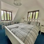 Bright bedroom with double bed and windows.