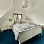 Modern bedroom with double bed and sloped ceiling.