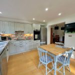 Modern kitchen with wooden table and white cabinets.