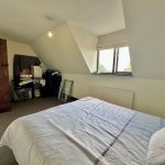 Cosy attic bedroom with window and wooden door.