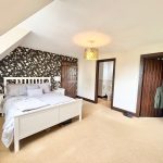 Spacious bedroom with double bed and floral wallpaper.