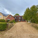 Traditional brick house with gravel driveway and trees.