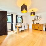 Modern dining room with wooden furniture and large clock.