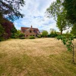 Spacious garden with a brick house in background.
