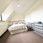 Loft bedroom with bed, shelves, sloped ceiling.