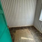 Empty room with patterned wallpaper and wooden floor.
