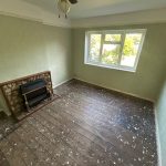 Empty room with wooden floor and fireplace.