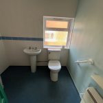 Small bathroom with sink, toilet, window and heater.