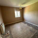 Empty room with unfinished wooden floor and window.
