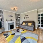 Modern living room with grey sofa and colourful rug.