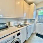 Modern utility room with appliances and white cabinets.