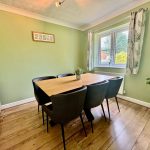 Green dining room with wooden table and chairs.