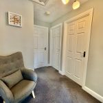 Bright hallway with armchair and three white doors.