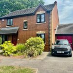 Brick house with driveway and parked car.