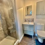 Modern bathroom with shower, sink, and toilet.