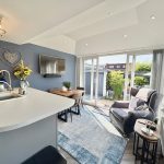 Modern kitchen-living area with large windows and seating.