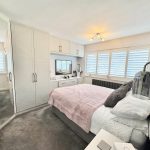 Cosy modern bedroom with mirrored wardrobe and soft lighting.