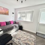 Modern white bedroom with daybed and colourful cushions.