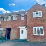 Brick terraced house with white windows and door.