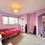 Purple bedroom with bed and bookshelf.