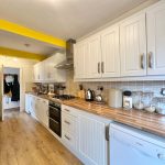 Modern kitchen with white cabinets and wooden countertops.