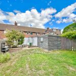 Back garden with grass, fence and shed.