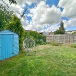 Backyard with blue shed and hanging chair.